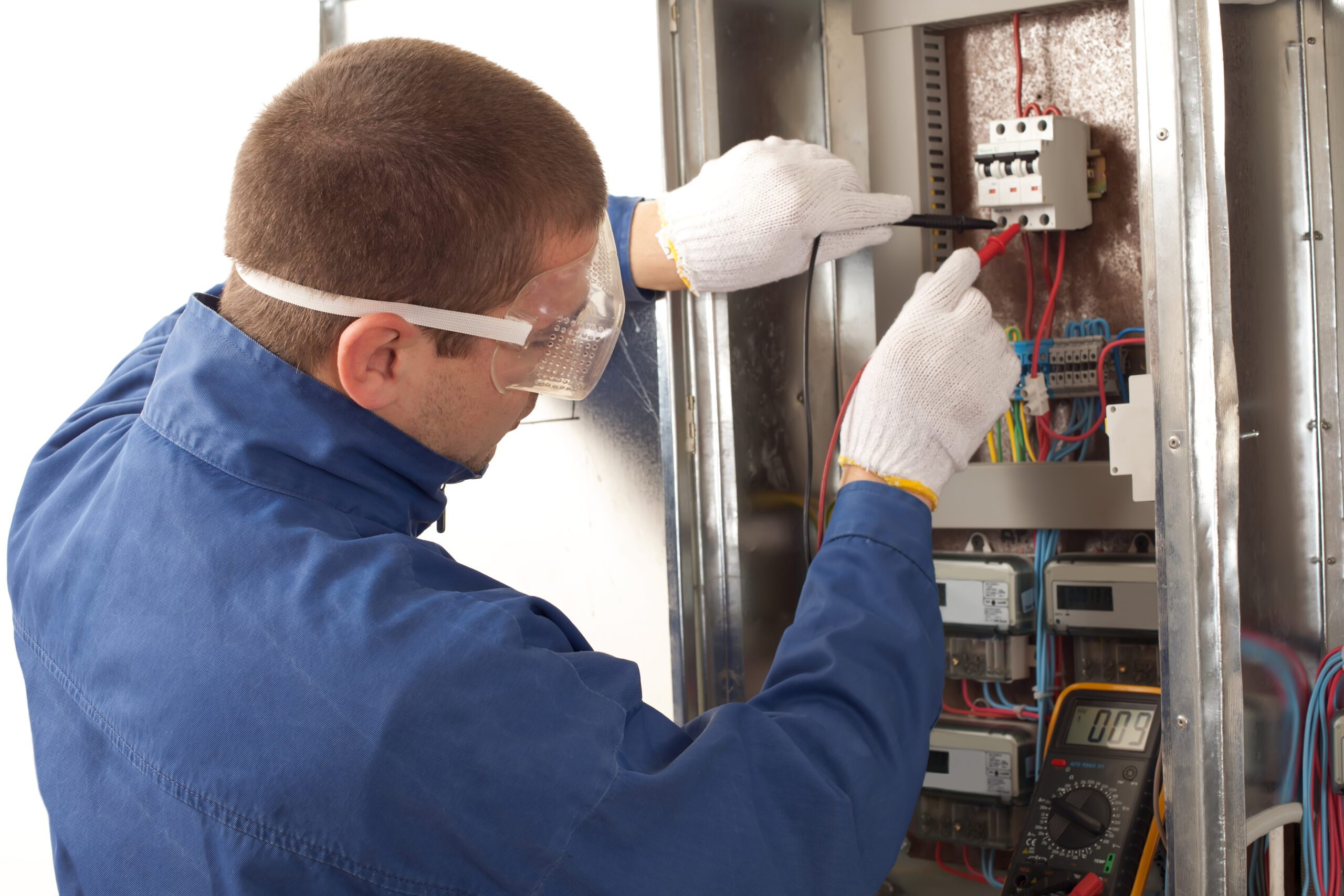 Electrician checking fuse box using a digital multimeter.